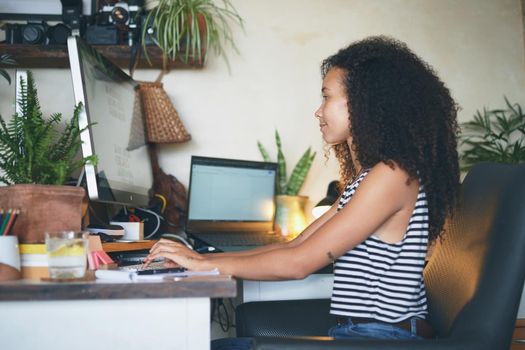 Shot of an attractive young african woman sitting alone and using her computer to work from home stock photo