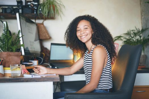 Shot of an attractive young african woman sitting alone and making notes in her home office - stock photo