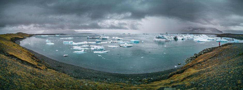 Spectacular panorama in Jokulsarlon with unrecognizable tourist admiring the landscape