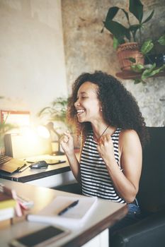 Shot of an attractive young woman sitting alone and celebrating a success while using her computer to work from home stock photo