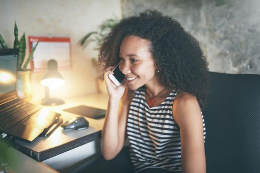 Shot of an attractive young african woman sitting alone and using technology while working from home stock photo