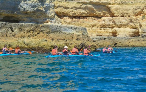 Group of people on canoe in the ocean with mountains. Kayaks.