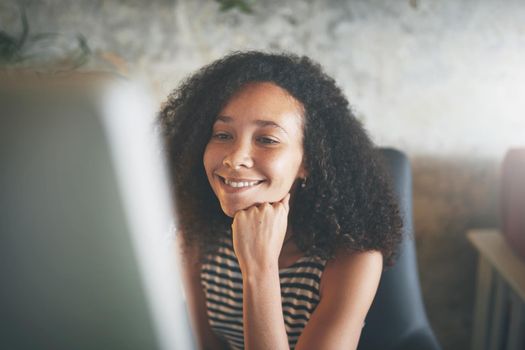 Shot of an attractive young african woman sitting alone and using her desktop pc while working from home stock photo