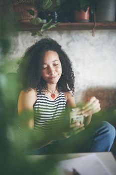 Shot of an attractive young woman sitting alone and using her cellphone while working from home stock photo