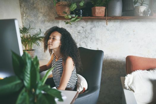 Shot of an attractive young african woman sitting alone and working on her desktop pc