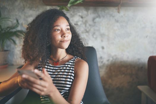 Shot of an attractive young african woman sitting alone and using technology while working from home stock photo