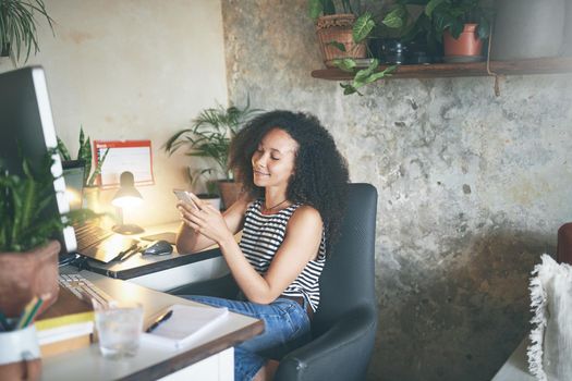 Shot of an attractive young woman sitting alone and using technology while working from home stock photo