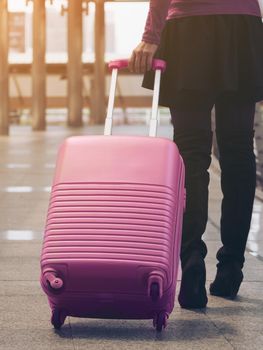 Woman traveller walking in airport walkway with travel bag or luggage. Traveler travel abroad through international airport terminal. Concept of woman travel, traveling lifestyle with travel bag.