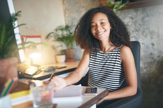 Shot of an attractive young african woman sitting alone and making notes in her home office - stock photo