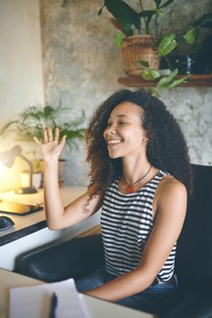 Shot of an attractive young african woman sitting alone and using her computer for a video chat while working from home stock photo