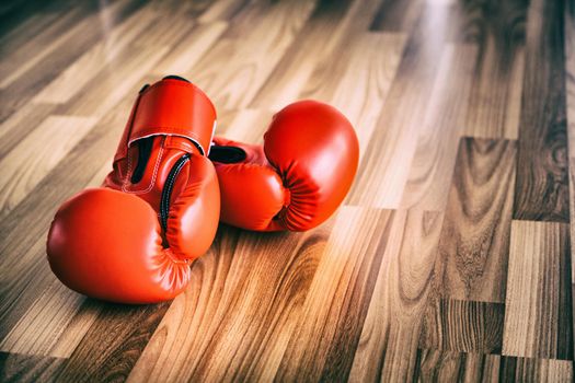 Red boxing gloves on wood background. Sport and healthy lifestyle concept.