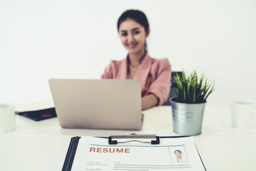 Resume or CV (curriculum vitae) document paper sent to businesswoman from human resources department sitting at table in office. Job application and hiring concept.
