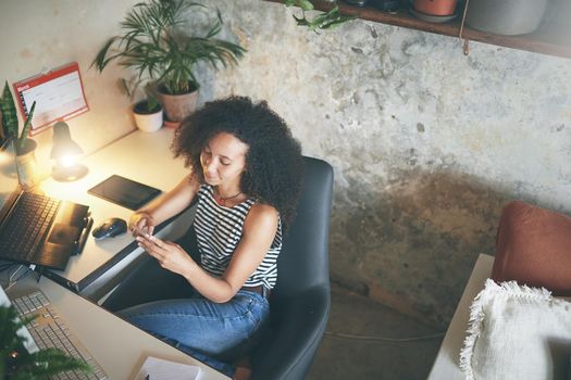 Shot of an attractive young woman sitting alone and using technology while working from home stock photo