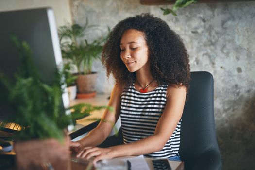 Shot of an attractive young african woman sitting alone and using her computer to work from home stock photo