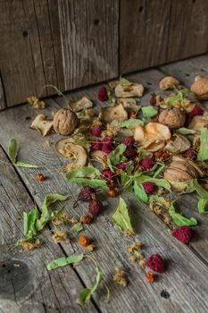 Dried delicious delicacies. Dry pieces of linden, rose hips, pears, raspberries, apples and walnuts snack on a wooden background.