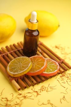 Essential oil bottle and lemon on yellow background ,