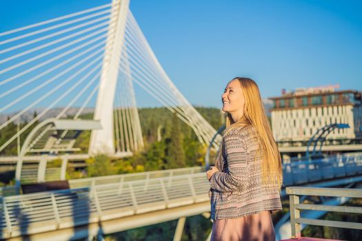 Woman tourist on the background of the Moscow footbridge in Podgorica. The metal construction of this pedestrian bridge was a gift by the city of Moscow to the people of Montenegro. Built in 2008 the modern design juxtaposes well with the nearby Millennium bridge.