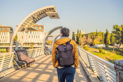 Man tourist on the background of the Moscow footbridge in Podgorica. The metal construction of this pedestrian bridge was a gift by the city of Moscow to the people of Montenegro. Built in 2008 the modern design juxtaposes well with the nearby Millennium bridge.