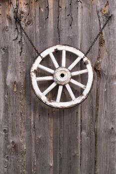 An old wooden carriage wheel hanging on the barn wall.