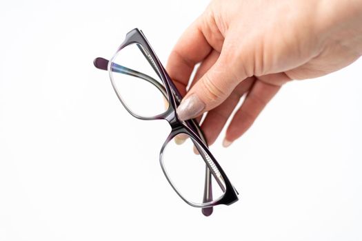 Glasses for vision correction in a female hand on white
