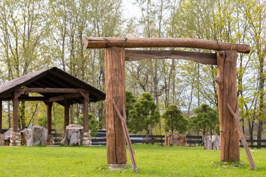 A wooden arch and a wooden gazebo standing on the territory next to the estate.