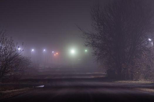 Poles with street lamps at night in the fog in the village, Russia