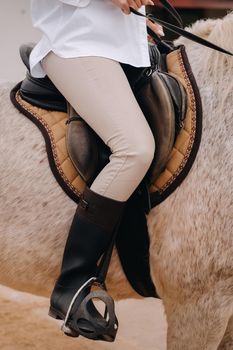 Close-up of a rider's legs in stirrups. A woman on a horse.