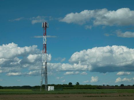 G5 cell phone tower base station against blue sky with clouds. Waves might increase the risk of health care issues.