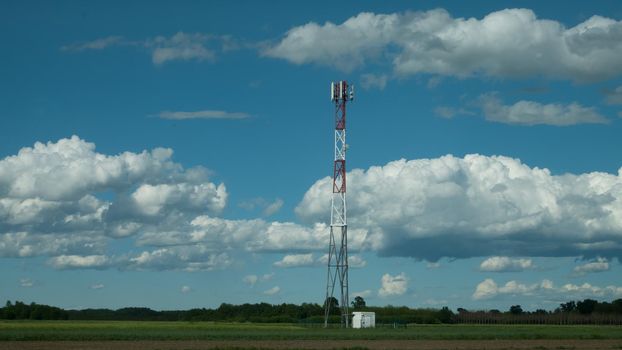 G5 cell phone tower base station against blue sky with clouds. Waves might increase the risk of health care issues.