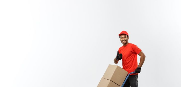 Delivery Concept - Portrait of Handsome African American delivery man or courier pushing hand truck with stack of boxes. Isolated on Grey studio Background. Copy Space