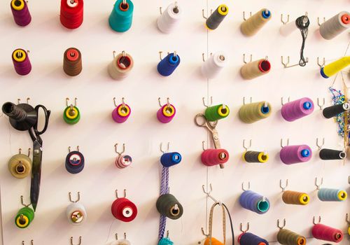 Multicolored coils and scissors on the wall. Workplace seamstresses