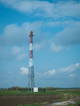 G5 cell phone tower base station against blue sky with clouds. Waves might increase the risk of health care issues.