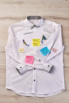 Vertical shot of white shirt with sticky notes. White desk background.