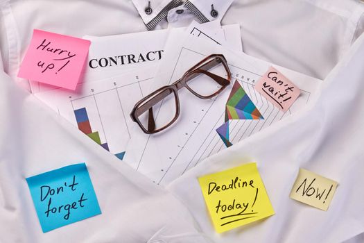 Glasses with sticky notes and contracts on the white shirt. Top view flat lay.