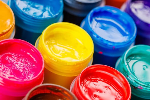 full-frame close-up background of opened small gouache paint jars on black