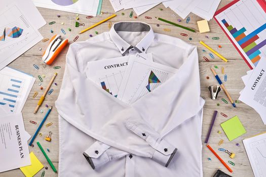 Top view white shirt with stationery workdesk stuff. Paperclips staplers pens etc.