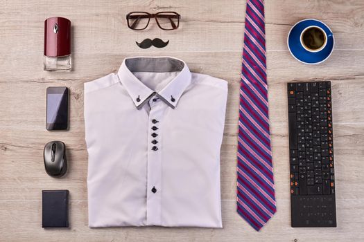 Flat lay top view concept of stylish office worker stuff on the desk. Folded shirt with glasses and tie.