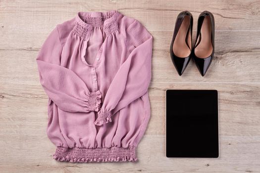 Shoes with blouse and tablet on white wooden desk. Top view flat lay.