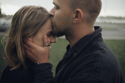 guy gently kisses his beloved holding hands on her face
