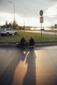 lovers eat pizza sitting on the lawn during sunset