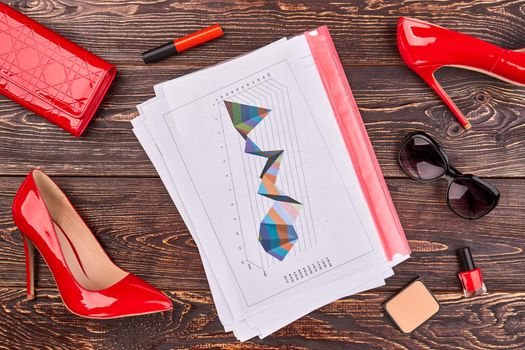 Red womens accessories and papers with statistc graphs. Female office worker stuff top view flat lay.