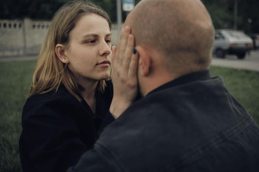 the girl looks at her boyfriend and is about to kiss him. the view from the back of a guy to a girl