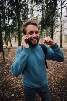 Young adult man talking on the phone standing over white brick wall stressed with hand on head, shocked with shame and surprise face, angry and frustrated. Fear and upset for mistake.