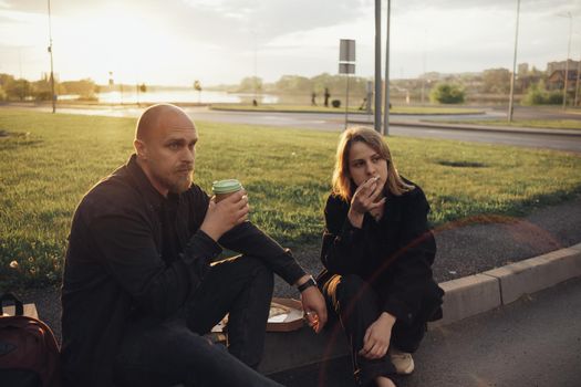 lovers eat pizza sitting on the lawn during sunset