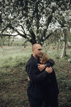 lovers embrace under a flowering tree hiding from the rain