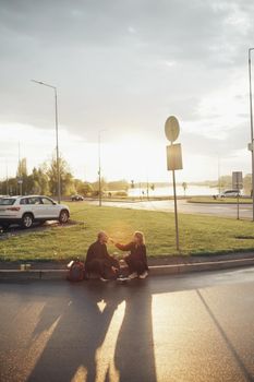 lovers eat pizza sitting on the lawn during sunset