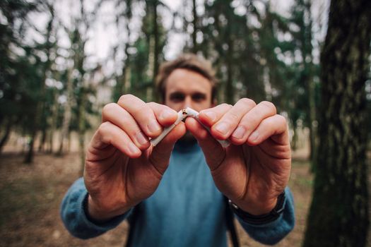 Doctor dentist breaks a cigarette, broken cigarette close up, background dental office. Stop Smoking.