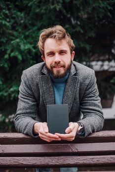 Portrait handsome bearded man wearing glasses blue shirt.Man near university library, reading book and relaxing. Blurred background.Horizontal, film effect.