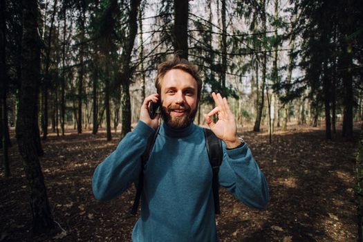 Young adult man talking on the phone standing over white brick wall stressed with hand on head, shocked with shame and surprise face, angry and frustrated. Fear and upset for mistake.