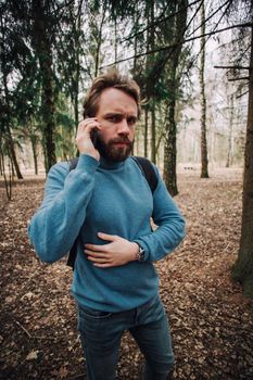 Young adult man talking on the phone standing over white brick wall stressed with hand on head, shocked with shame and surprise face, angry and frustrated. Fear and upset for mistake.